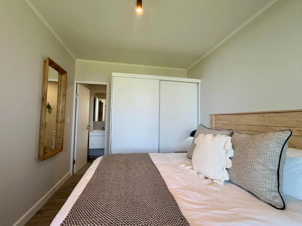 Bright bedroom with wooden bed frame and neutral bedding setup