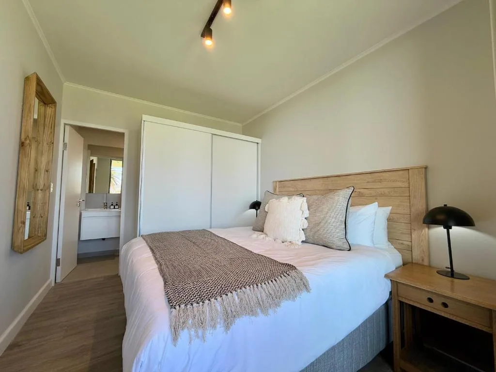 Bright bedroom with wooden bed frame and ensuite bathroom access
