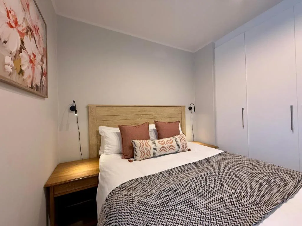 Modern bedroom with wooden headboard, decorative pillows, and built-in wardrobe