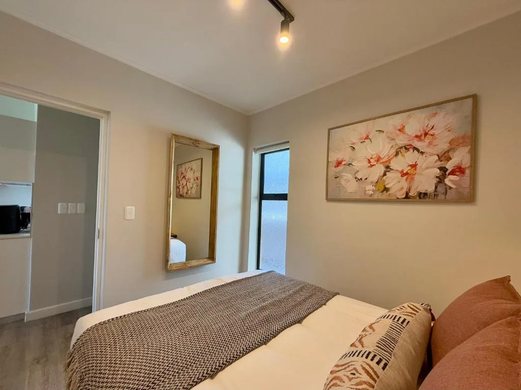 Modern bedroom with queen bed, floral artwork, and garden view window