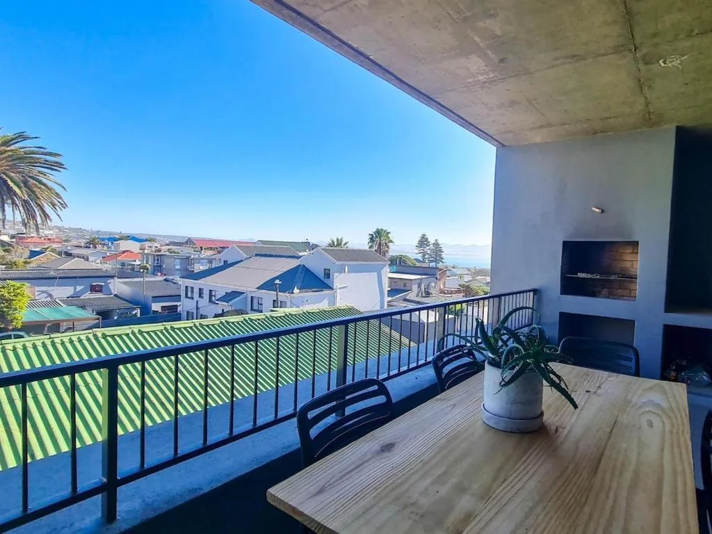 Spacious balcony with panoramic town and coastal views, wooden table, modern railing