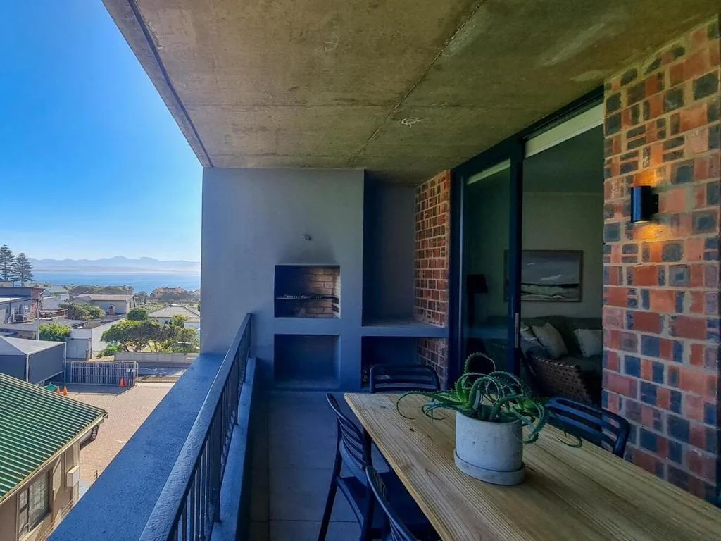 Modern balcony with ocean views, potted plant, and coastal scenery beyond