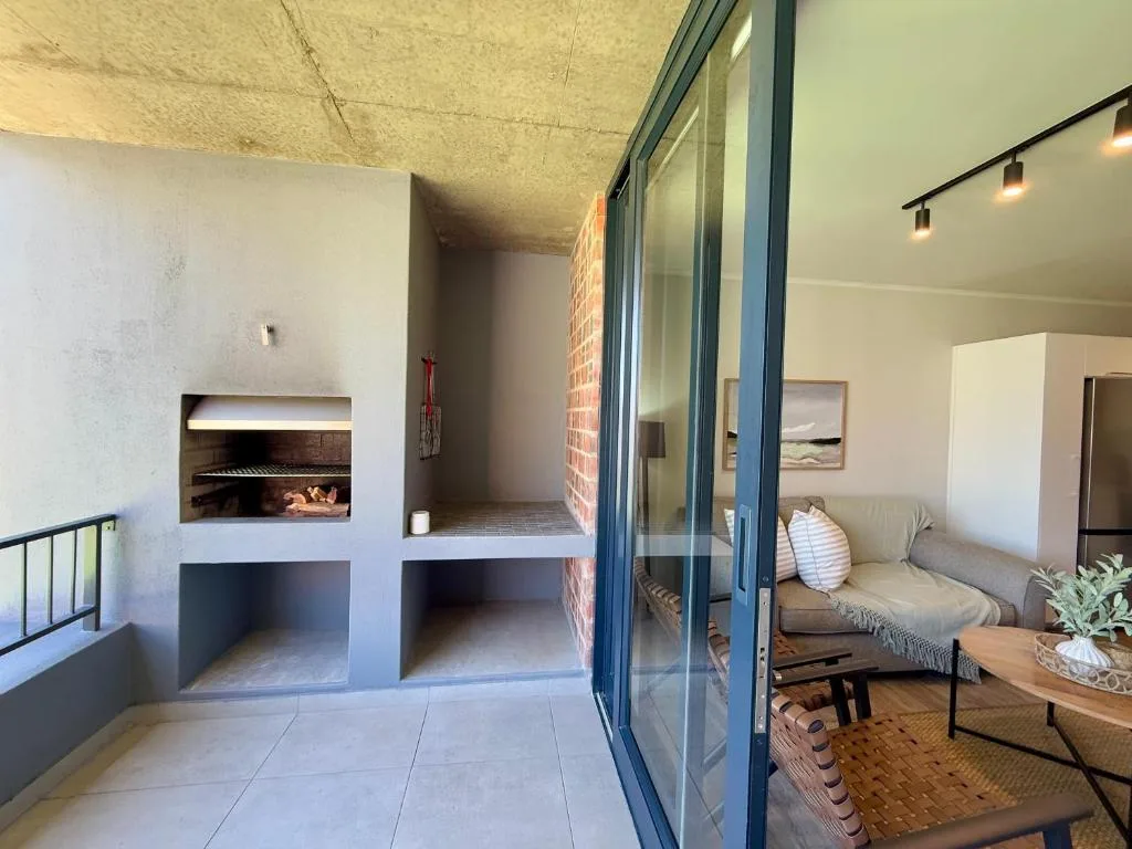 Modern outdoor deck with built-in braai and seating area overlooking interior lounge