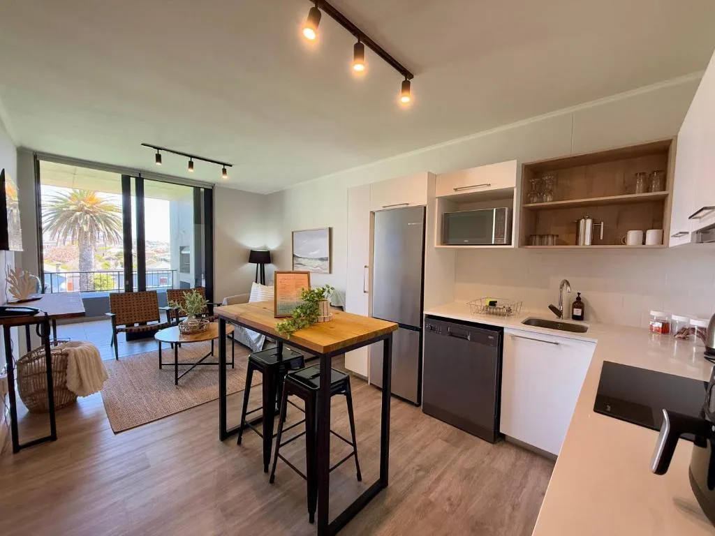 Modern dining area with wooden table, black chairs, and open-plan kitchen