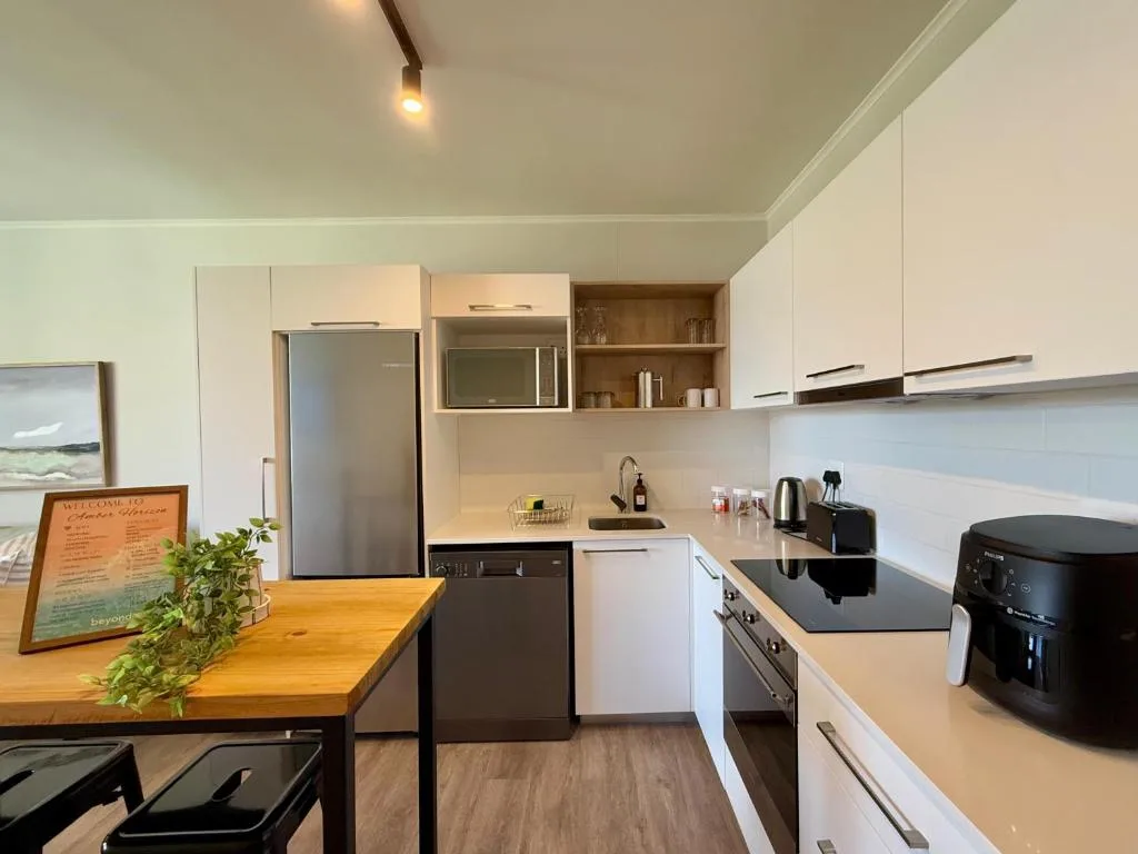 Modern kitchen with white cabinetry, stainless steel appliances, and wooden dining counter