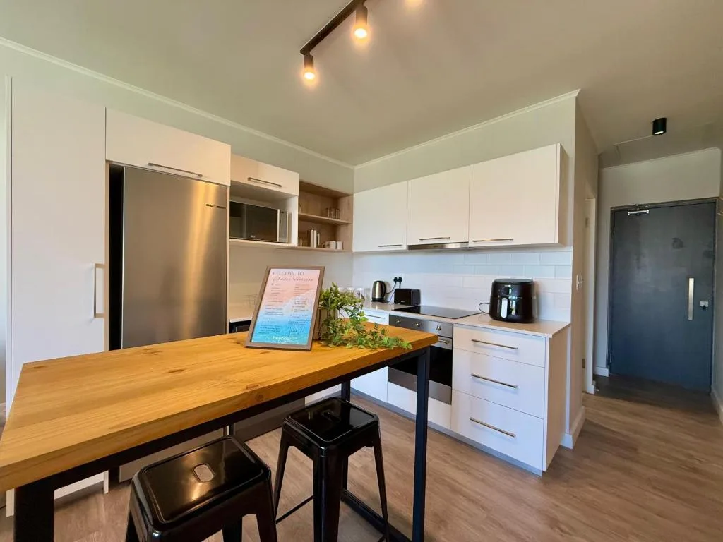 Modern kitchen with white cabinetry, stainless steel fridge, wooden counter and bar seating