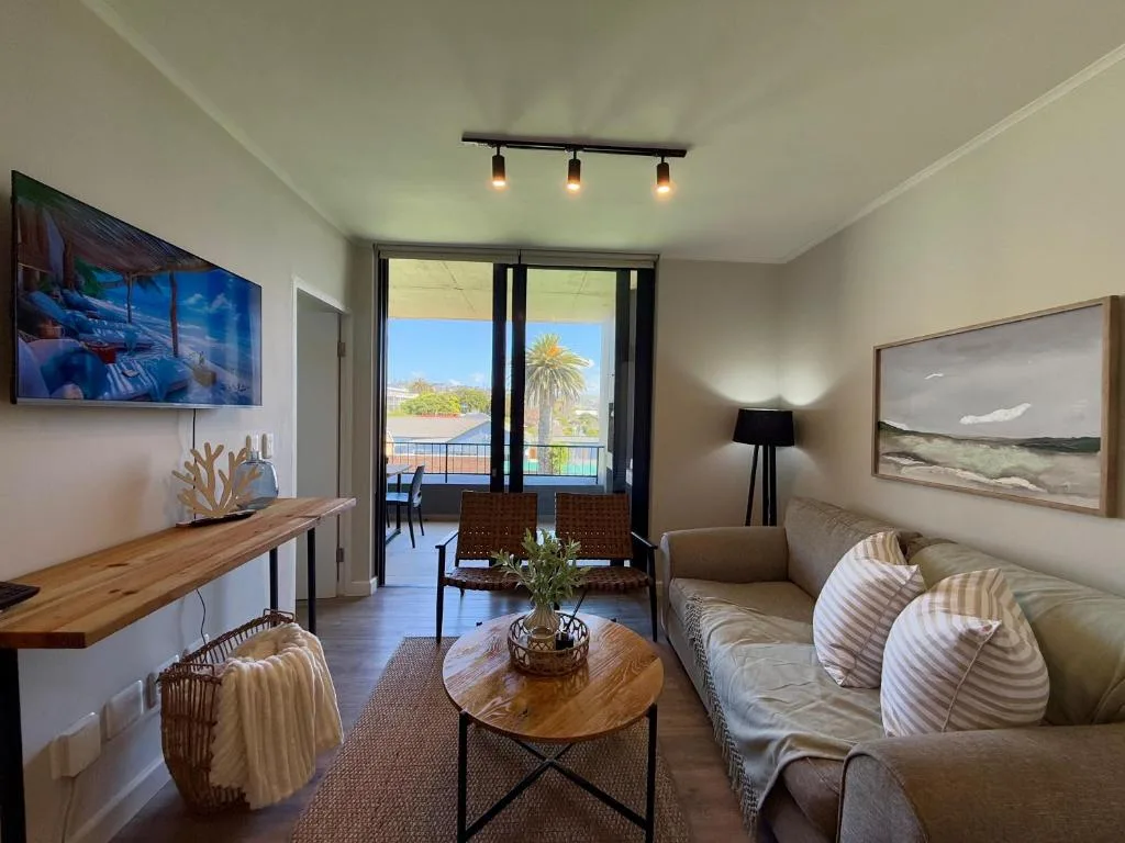 Spacious lounge with sofa, TV, wooden desk, and ocean view doors