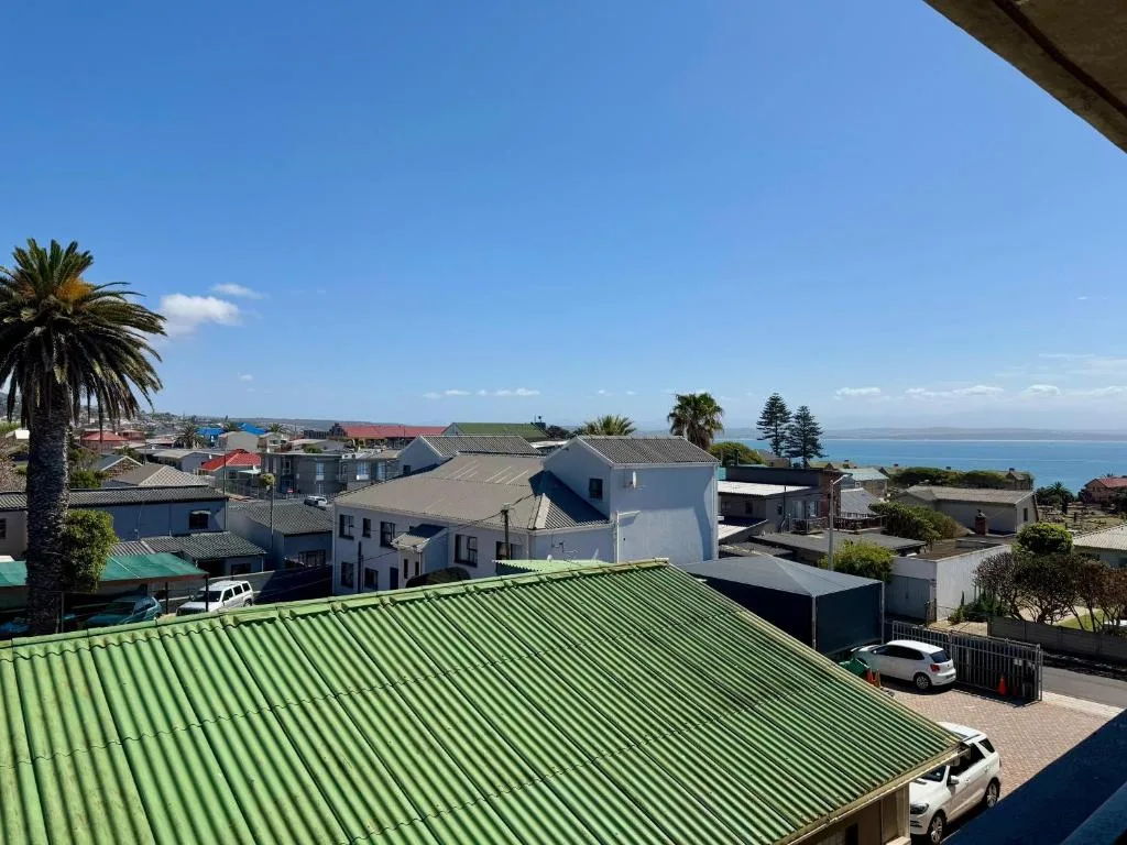 Coastal town vista with sea horizon, palm trees, and residential rooftops