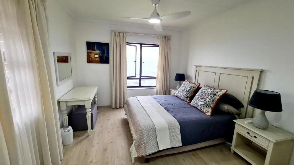 Spacious bedroom with queen bed, cream furniture, and balcony access