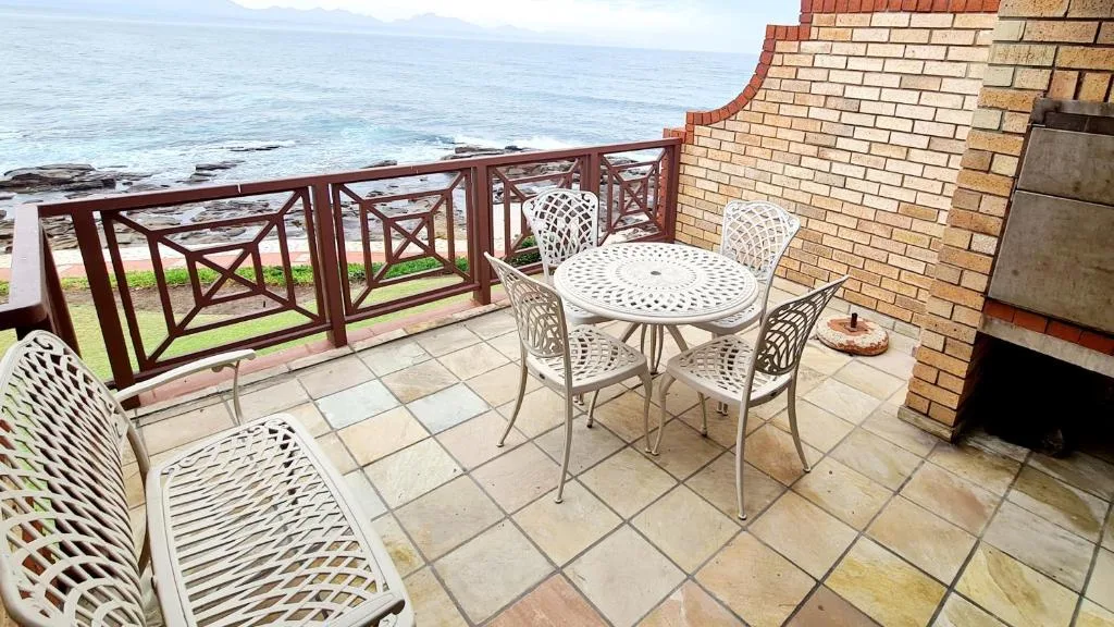 Oceanfront patio with white metal dining set and ocean view railing