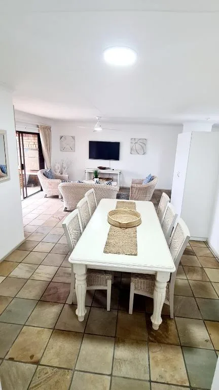 White dining table with woven chairs in open-plan living space