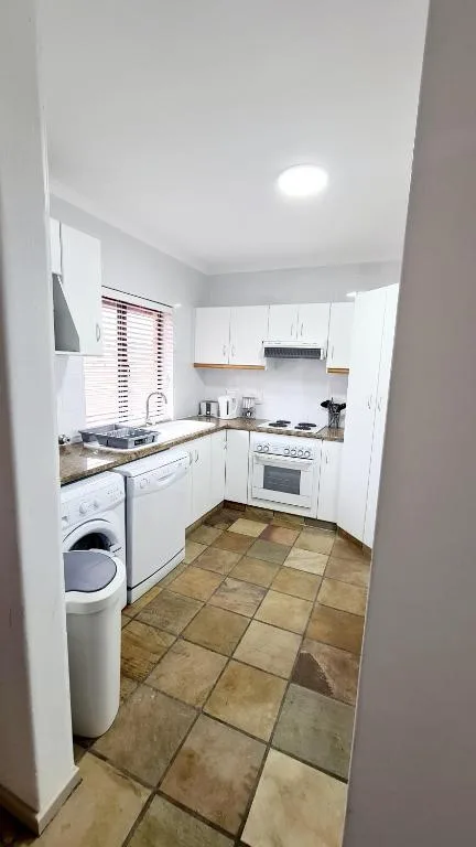 Compact white kitchen with stove, oven, and washing machine appliances