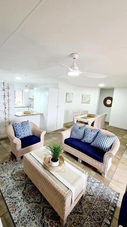 Bright living room with wicker furniture and blue cushions, ceiling fan overhead