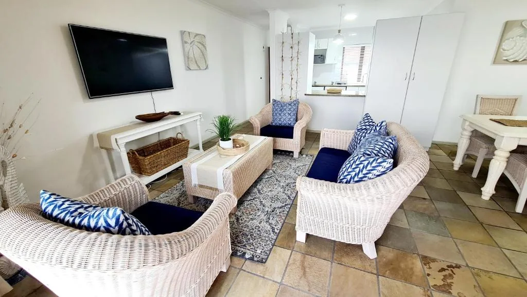 Bright lounge with wicker seating, wall-mounted TV, and blue accents
