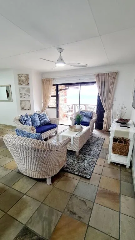 Bright lounge with wicker seating, blue cushions, and ocean view doors