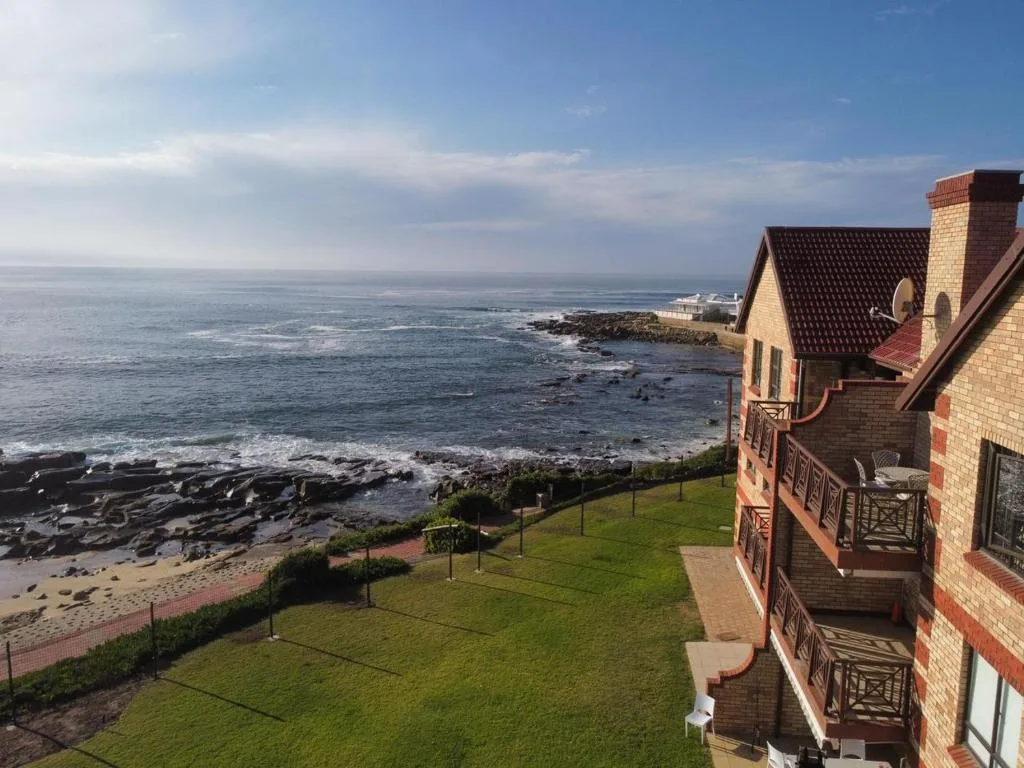 Scenic coastal ocean view with rocky shoreline and green lawn