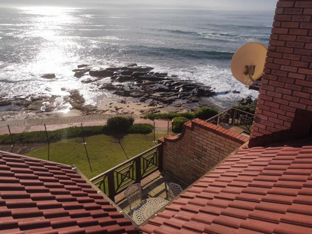 Stunning ocean and rocky beach view from property with manicured lawn