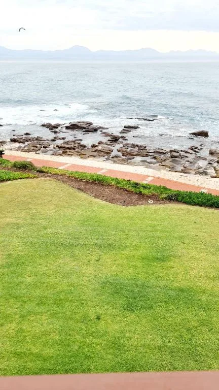 Ocean view with rocky coastline and distant mountains from lawn