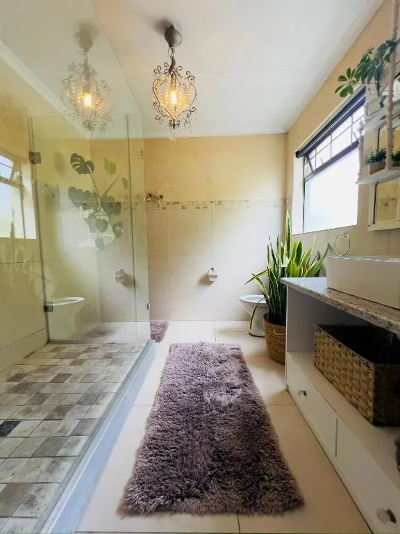 Spacious bathroom with walk-in shower, vanity, plants, and decorative pendant lights