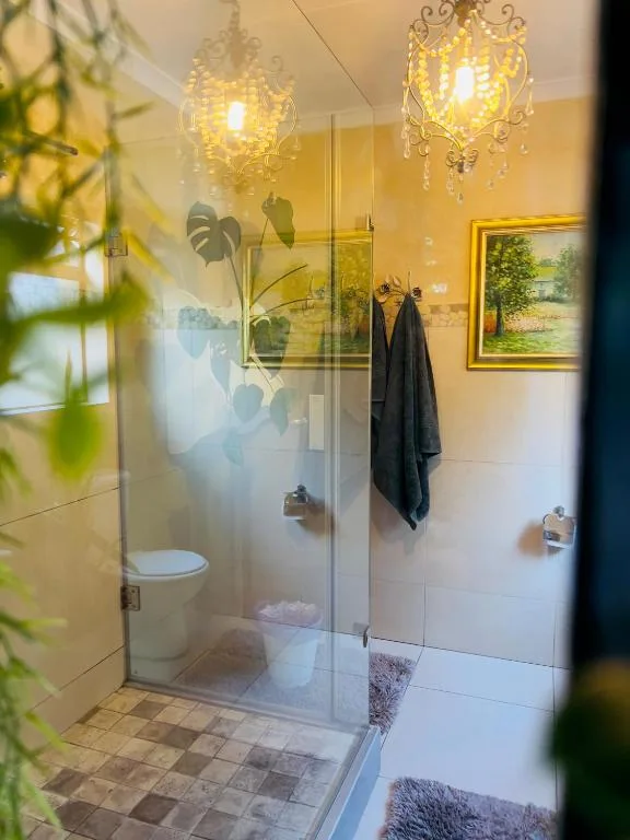 Modern bathroom with walk-in shower, decorative pendant lights, and potted plants