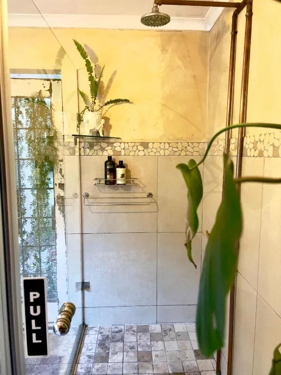 Bright yellow bathroom with glass shower enclosure and potted plants