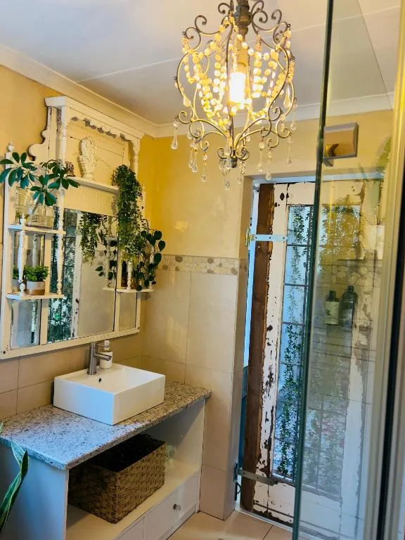 Bright yellow bathroom with vessel sink, ornate chandelier, and shower enclosure