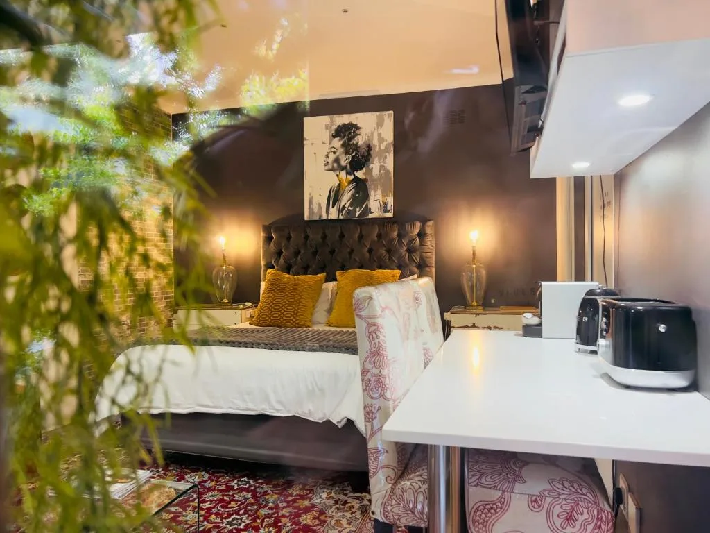 Modern bedroom with black upholstered headboard, golden pillows, and contemporary art
