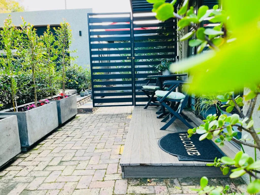 Modern patio with lounge chairs, slatted gate, potted plants, welcome mat