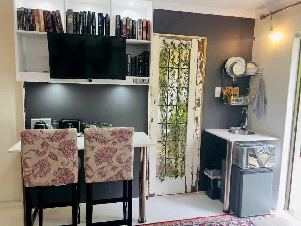 Open-plan kitchenette and lounge area with books, TV, and compact appliances