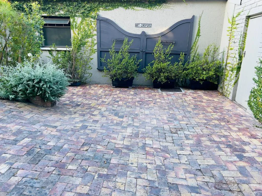 Brick paved driveway with blue gates and climbing ivy plants