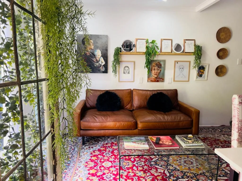 Modern lounge with cognac leather sofa, gallery wall art, and hanging plants
