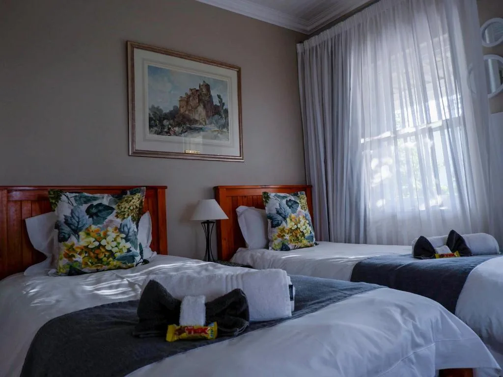 Twin bedroom with wooden headboards, floral pillows, and bright curtains