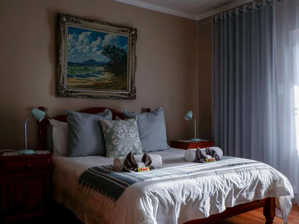 Elegantly appointed bedroom with white bedding, wooden headboard, and landscape artwork