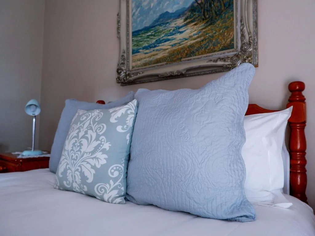 Bed with blue quilted pillows and white sheets, wooden headboard visible