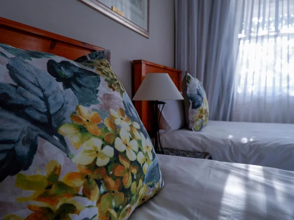 Bedroom with decorative floral pillows, wooden bedframe, and bright natural light