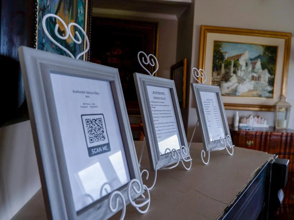 Framed QR code signs and information cards displayed on wooden table