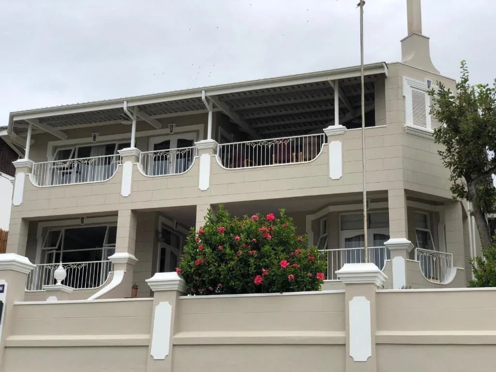 Cream-colored two-story apartment building with white railings and pink flowers
