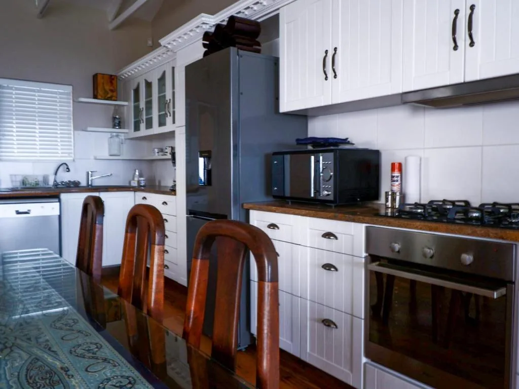 Modern kitchen with white cabinetry, stainless steel appliances, wooden countertops