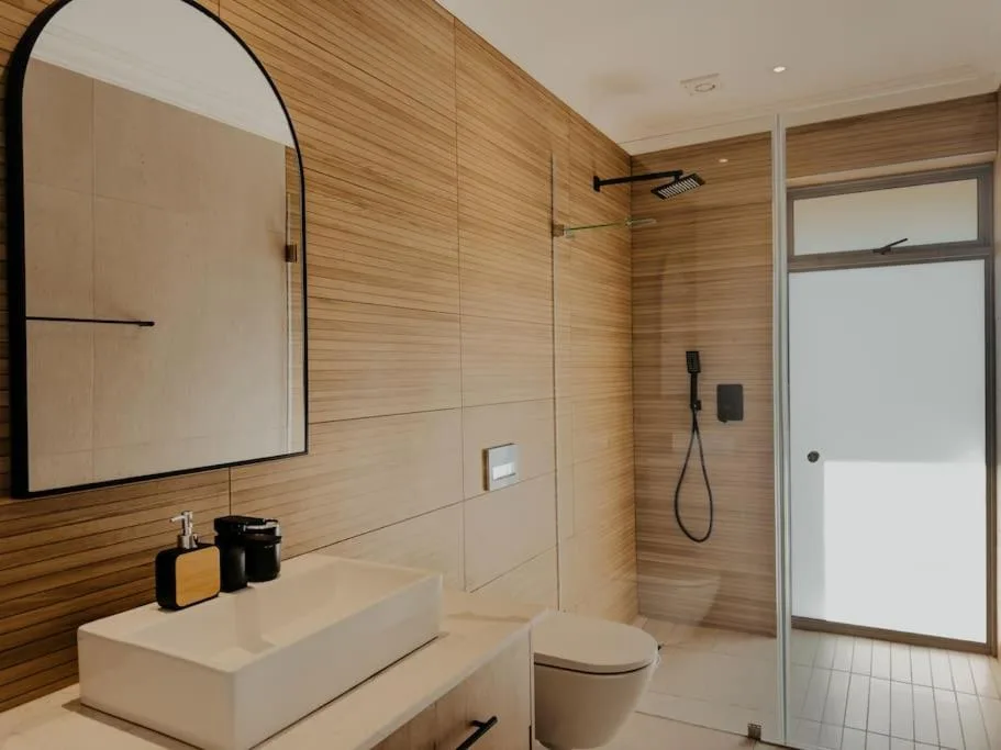 Modern bathroom with wood-tiled walls, vessel sink, and walk-in shower