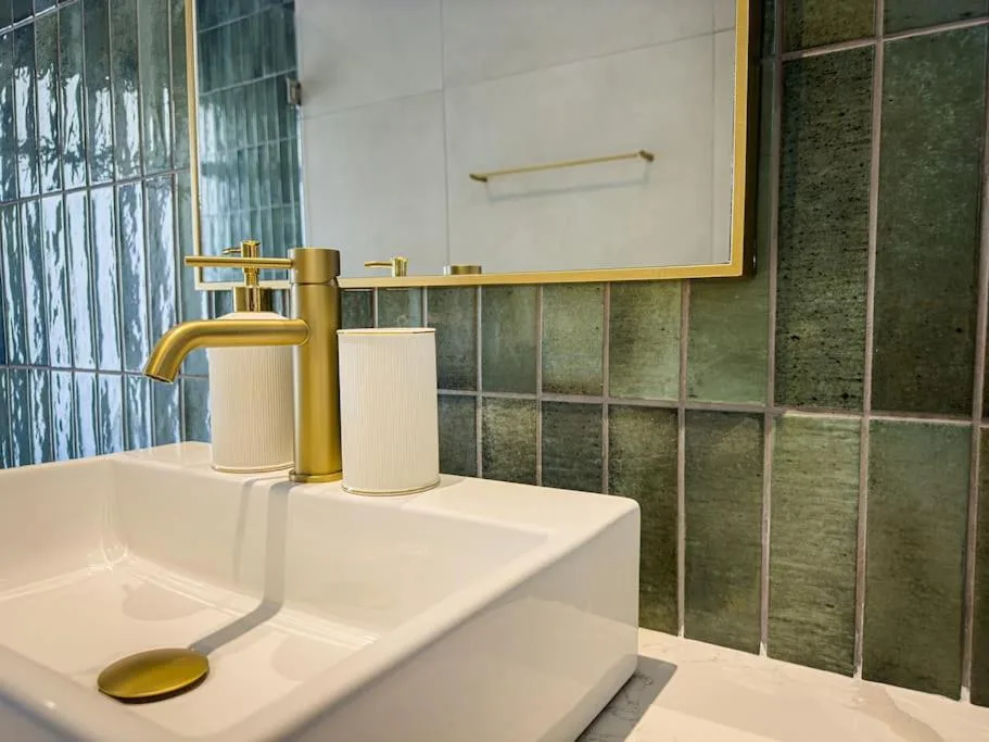 Modern bathroom vanity with brass faucet and green tile backsplash