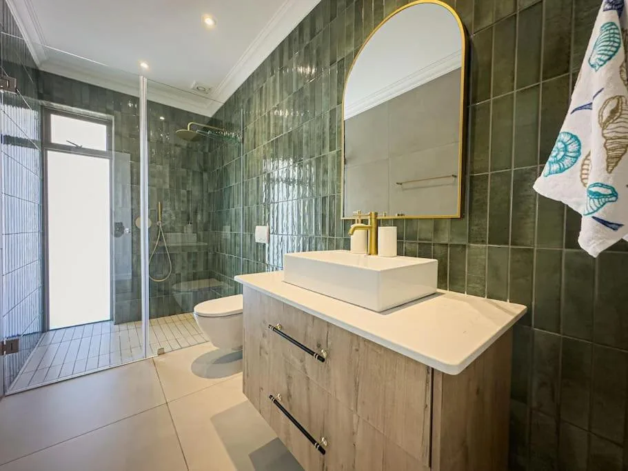 Modern bathroom with green tile walls, vessel sink, and glass shower enclosure