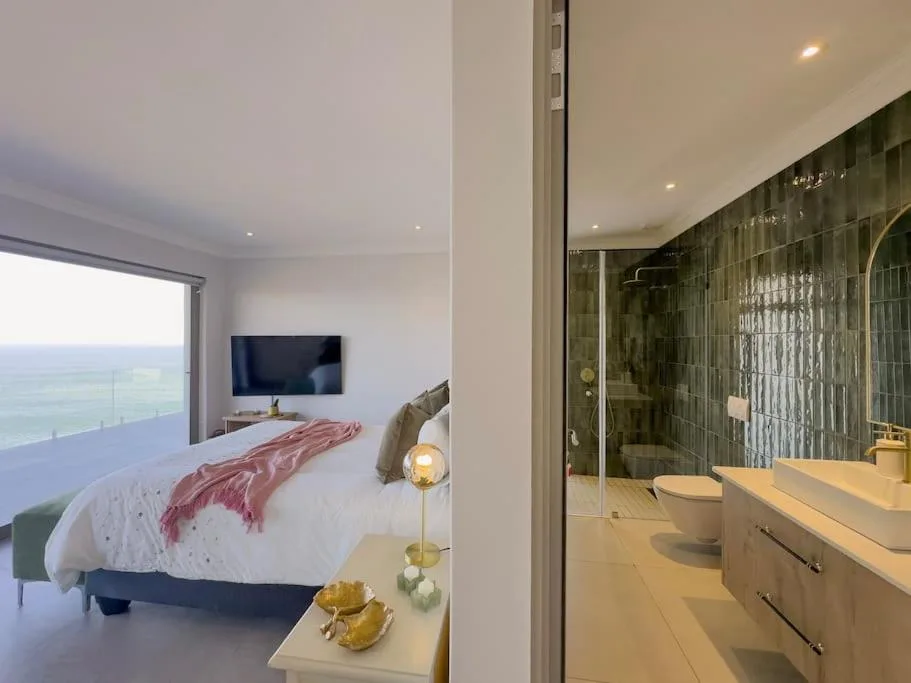 Modern bedroom with ocean view, en-suite bathroom visible through open door