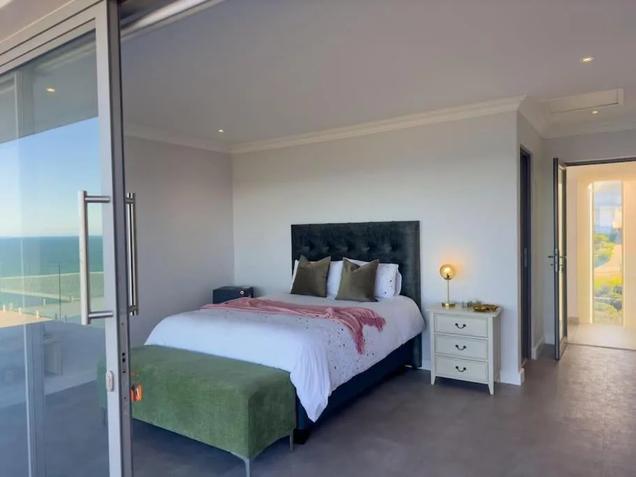 Modern bedroom with black upholstered headboard, ocean view through sliding glass doors