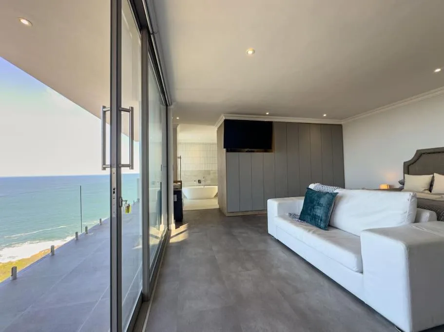Modern bedroom with ocean view, white bed, and en-suite bathroom