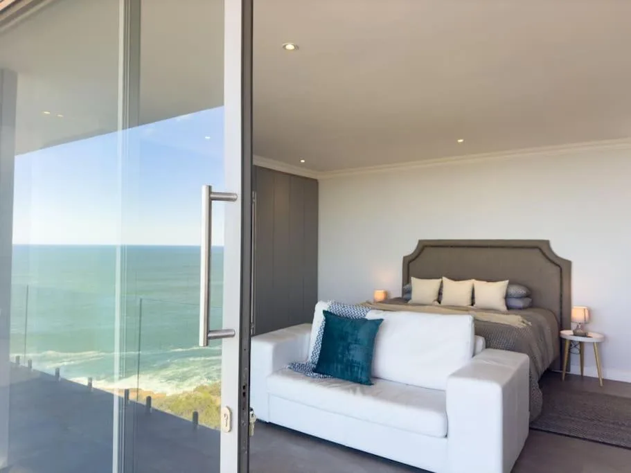 Modern bedroom with ocean view through floor-to-ceiling windows and contemporary furnishings