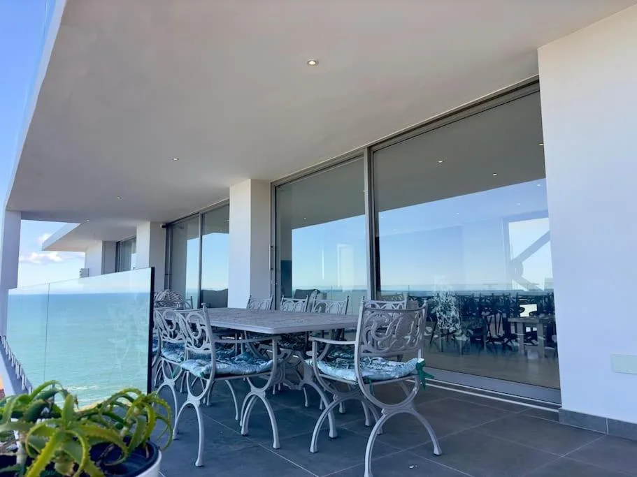Outdoor dining area with ocean view and modern white chairs