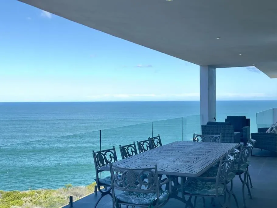 Oceanfront deck with dining table overlooking turquoise sea and horizon