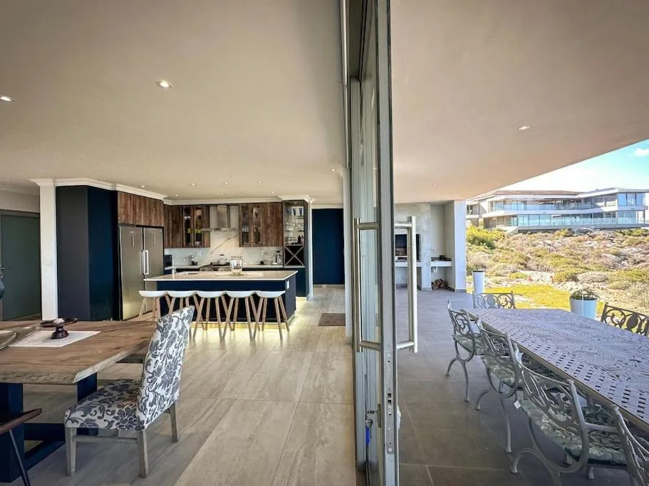Modern dining area with outdoor deck and kitchen view beyond