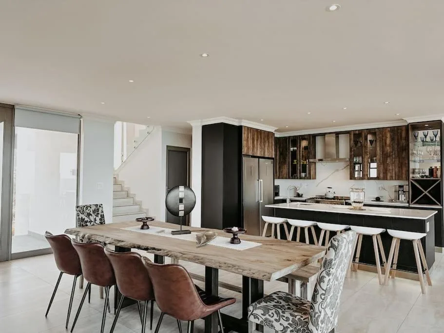 Modern dining area with wooden table and burgundy chairs, adjacent open kitchen