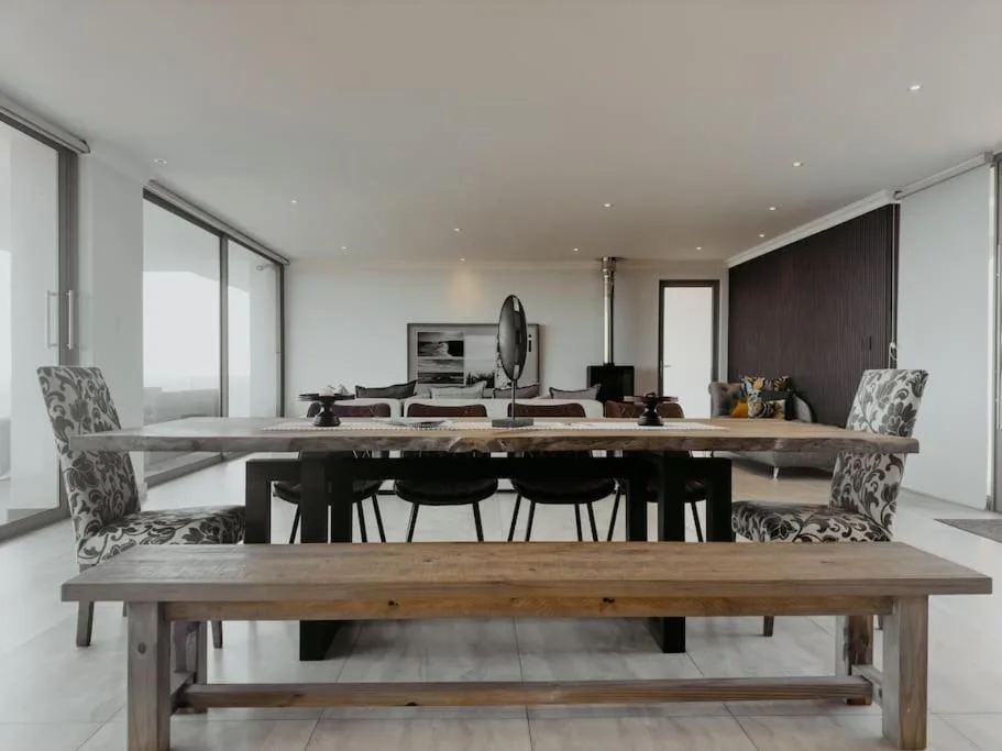 Modern dining area with wooden table and patterned chairs overlooking lounge space